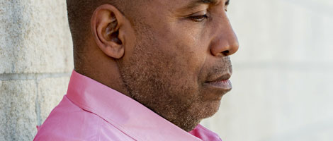 The side profile of an adult African American male wearing a pink collared button down shirt