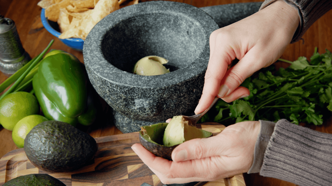 A person scooping avocado into a bowl