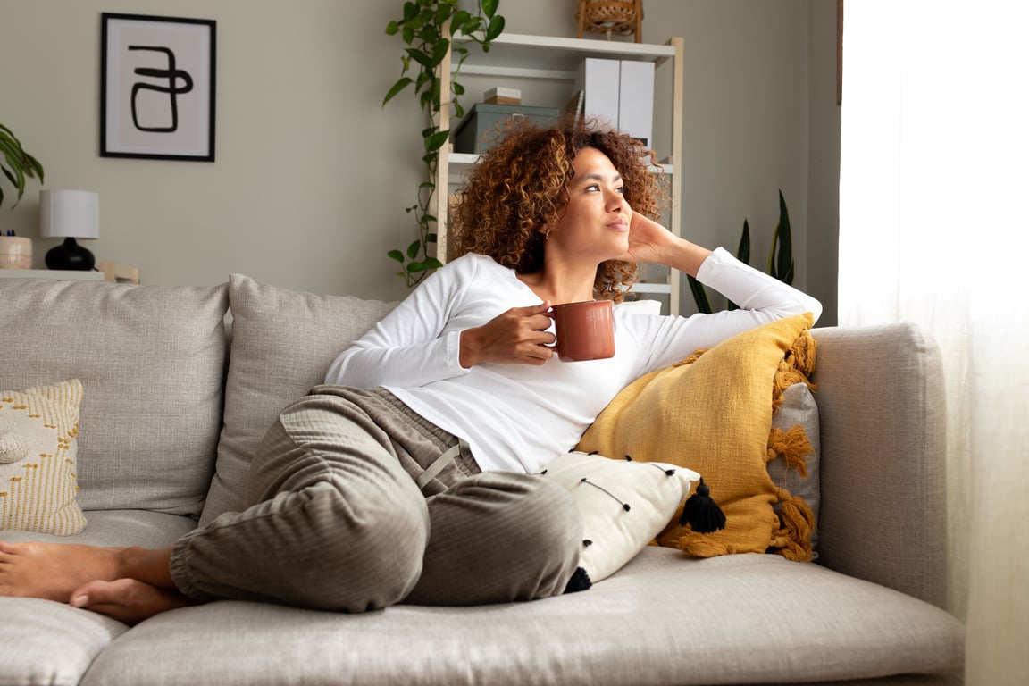A woman drinking coffee on her couch