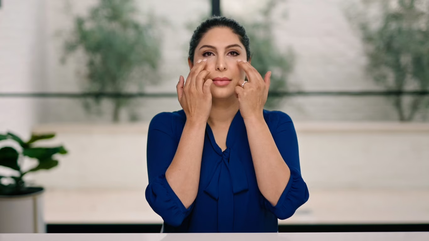 A woman tapping on her cheekbones with her fingers