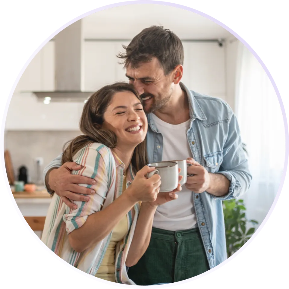A couple smiling together in their kitchen, holding mugs
