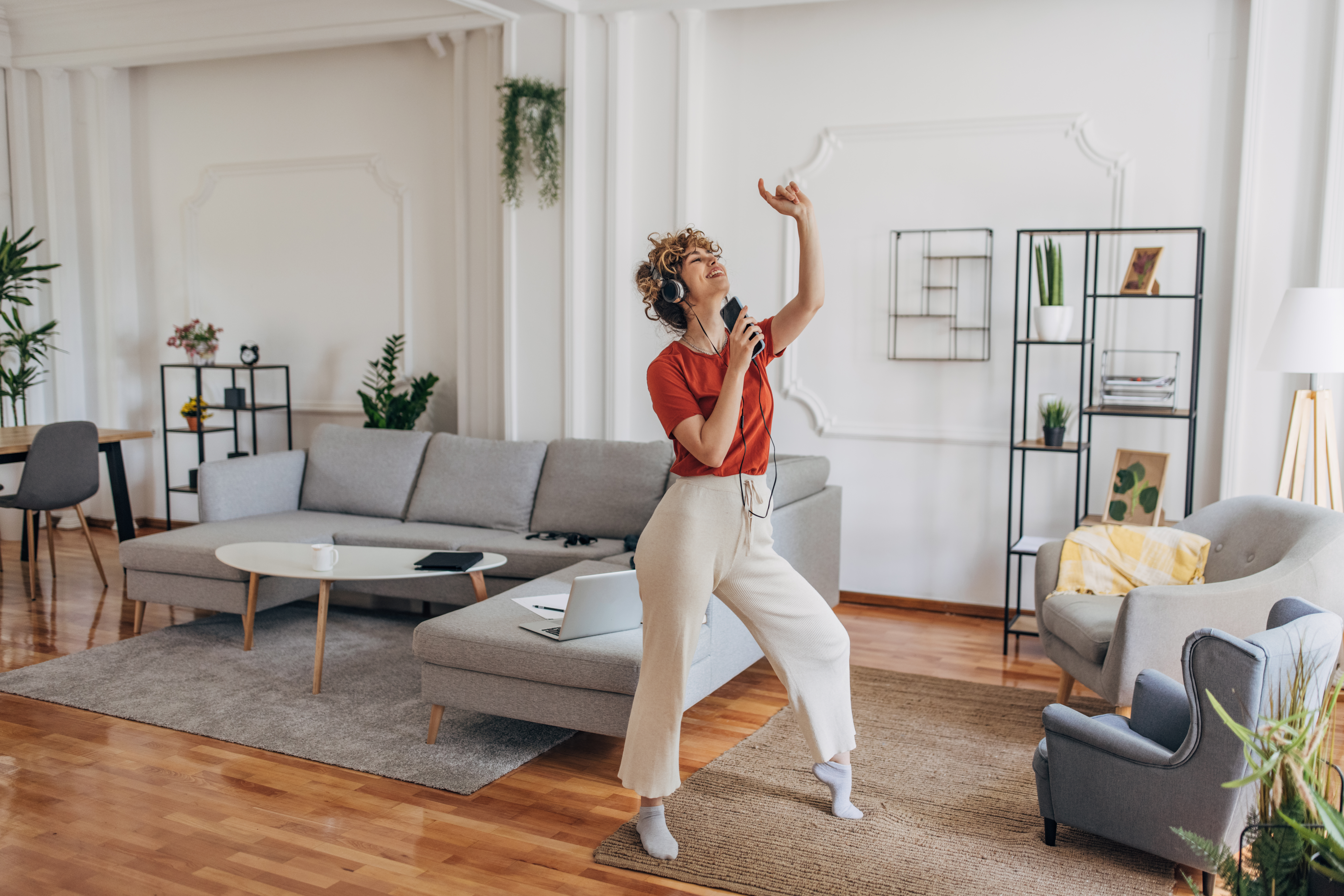 A woman wearing headphones and dancing in her home