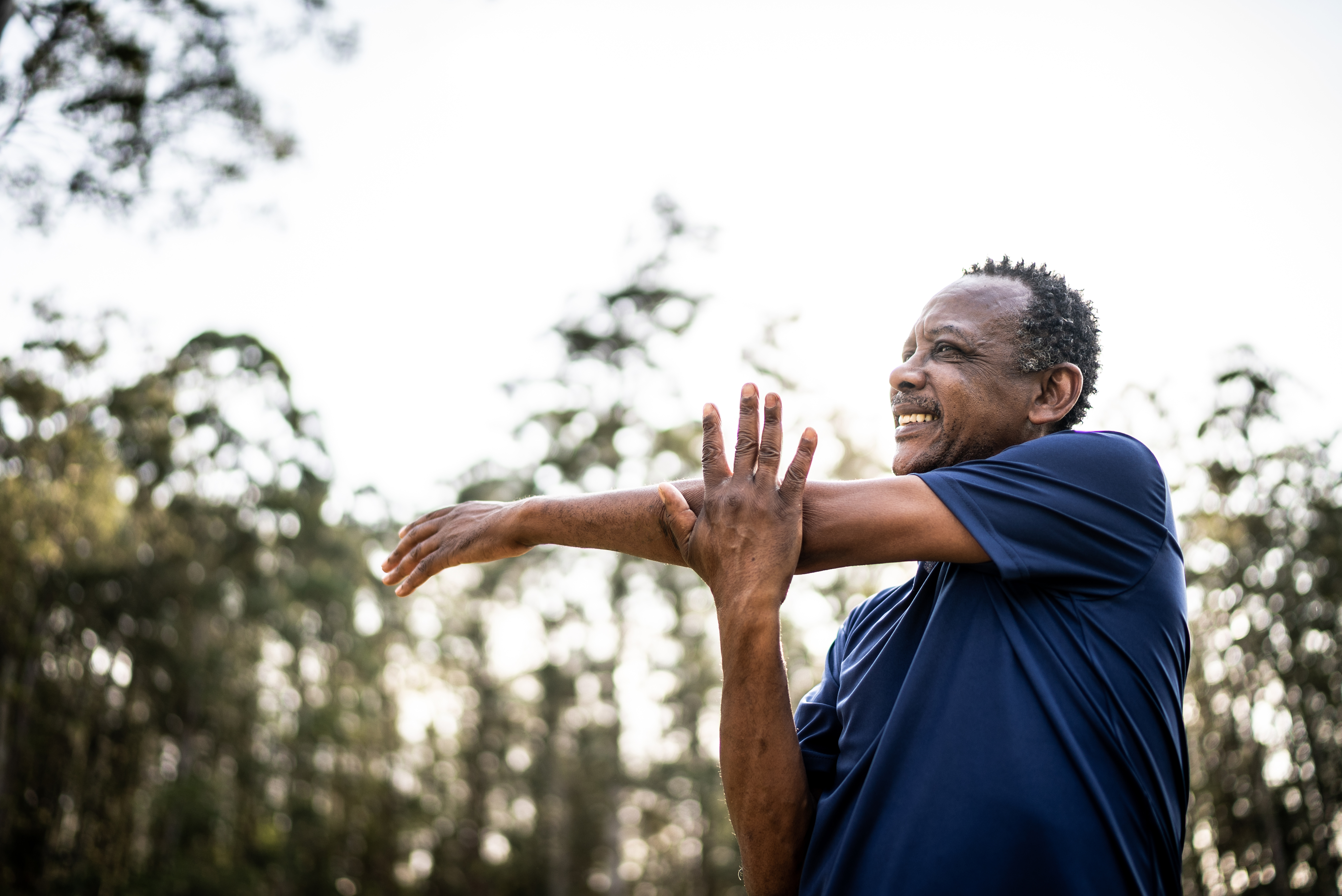 A senior man stretching his arm outside